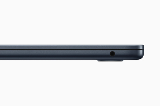 Close-up of a dark gray laptop edge showing a small circular port or speaker opening.