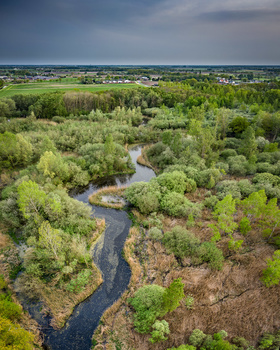 Winding river cutting through forested landscape with agricultural fields visible in the distance.