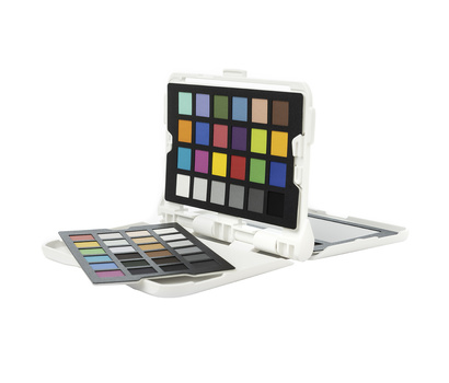 Color checker reference card with swatches displayed on white stand alongside printed color reference charts.