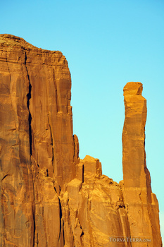 Tall golden-red rock formations silhouetted against a clear blue sky.