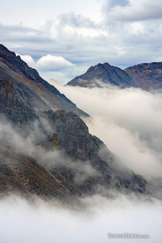 Rocky mountain peaks emerging above a thick layer of clouds and mist.