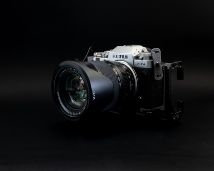 Fujifilm mirrorless camera with attached lens, photographed against a dark background.