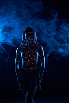 Figure in dark silhouette wearing glowing red geometric lines against blue smoke background.