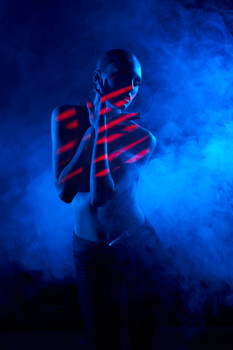 Person wearing red and blue striped fabric wrapped around torso against blue atmospheric background with smoke.