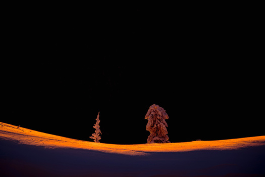 Two rocky peaks silhouetted against an orange atmospheric glow on the horizon at twilight.