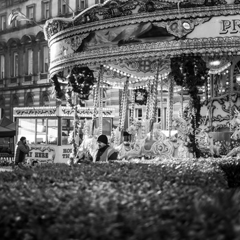 Black and white photograph of an ornate storefront decorated with garland and wreaths during holidays.