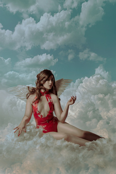 Woman with fairy wings sitting among clouds against a turquoise sky.
