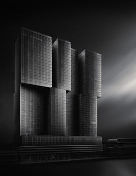 Modern brutalist architecture with three vertical concrete cylindrical towers against dark sky with dramatic lighting.