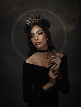 Woman with dark hair and crown wearing off-shoulder black garment against dark background with halo effect.