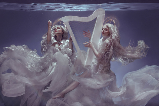 Two figures in flowing white gowns pose with a harp in an underwater-themed composite image.