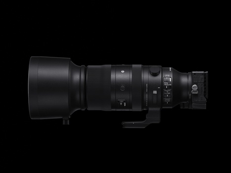 Side profile of a black telephoto lens with barrel hood and control rings against a dark background.
