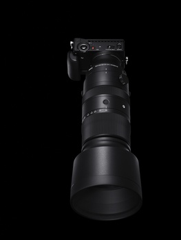 Black telephoto lens with camera body mounted on top, isolated against black background.