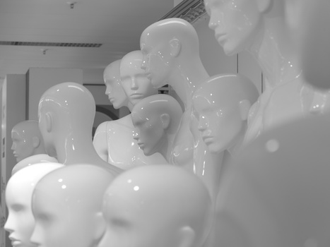 Row of white glossy mannequin heads displayed in an indoor studio or retail space.