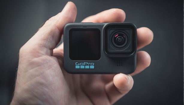 GoPro Hero 11 action camera held in palm, showing dual-screen design with front display and side lens.