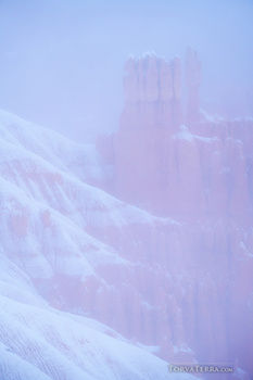 Snow-covered mountainside with distant castle towers shrouded in mist and purple atmospheric haze.