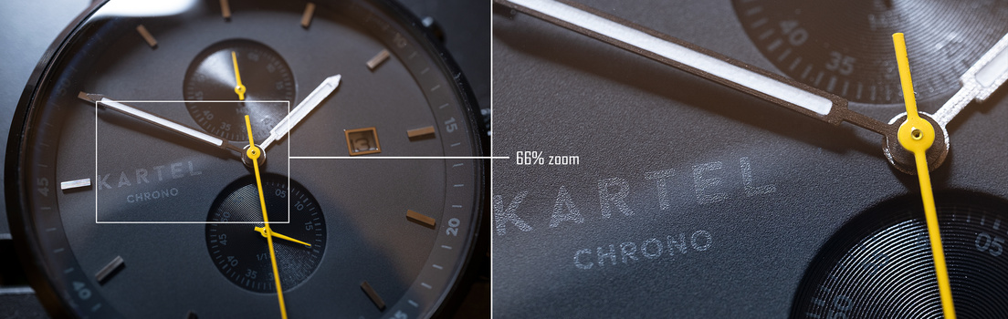 Close-up of a chronograph watch face with yellow hands and dark dial, showing brand text and subdials.