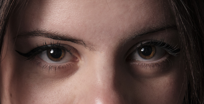 Close-up of a person's eyes with one eye open and one closed, showing detail in the iris and eyelashes.