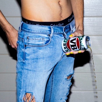 Male model wearing distressed blue jeans and holding a colorful toy robot against hip.