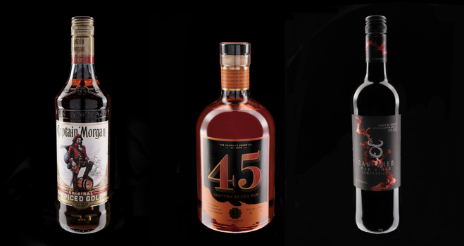 Three dark spirit bottles arranged against a black background with product labels visible.
