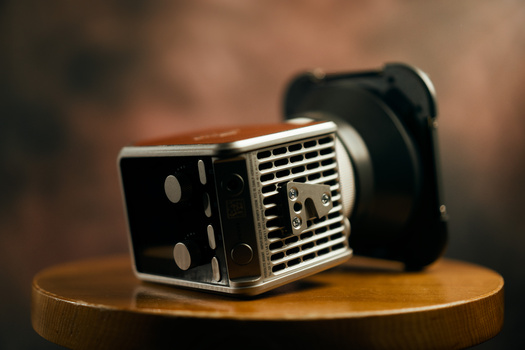 Vintage film camera with chrome details and black leather strap on wooden surface.