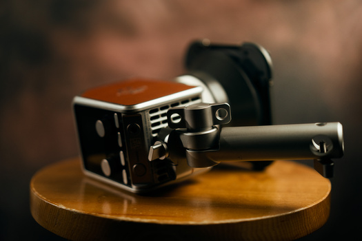 Vintage film movie camera with leather strap displayed on wooden surface.
