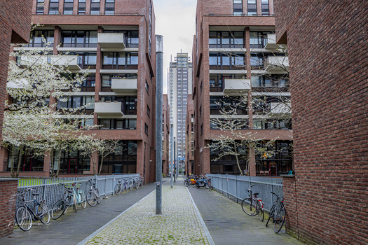 Symmetrical brick buildings frame a pedestrian walkway with bicycles parked on both sides.