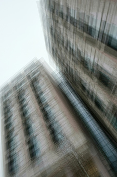Upward view of modern high-rise buildings with motion blur effect creating vertical streaking.