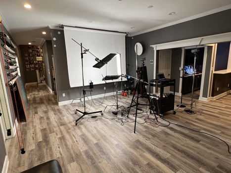Professional photography studio setup with lighting equipment, backdrop stand, and ring light in residential space.