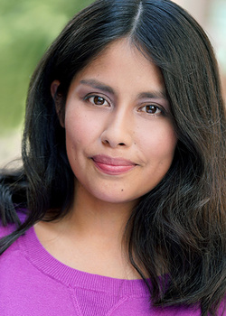 Woman with long black hair wearing a bright magenta ribbed sweater, photographed outdoors with soft natural lighting.