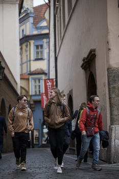 Three people walking down a narrow European cobblestone street lined with historic buildings.