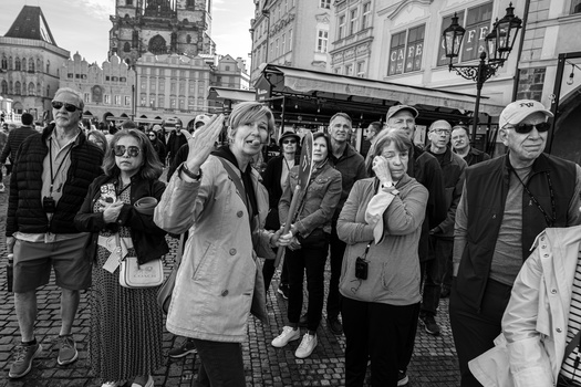 Crowd of tourists gathered in a European town square, photographed in black and white.