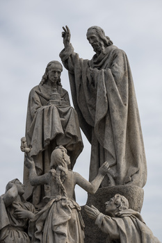 Stone monument featuring multiple robed figures in classical style against overcast sky.