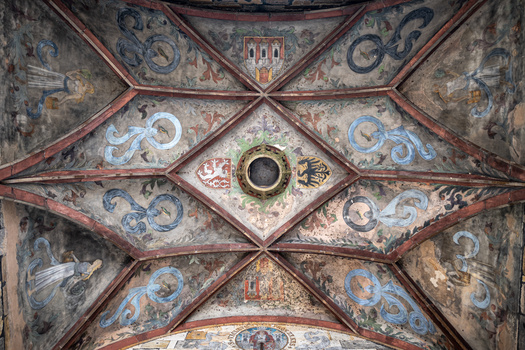 Ornate ceiling with symmetrical geometric design, decorative frescoes, and central oculus opening.
