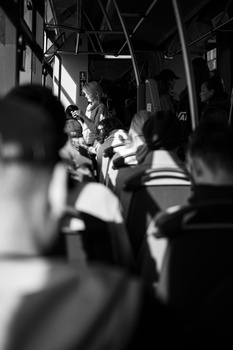 Black and white photograph of passengers seated inside a public transit bus during daytime.