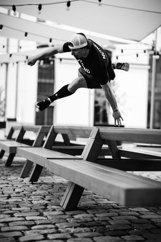 Parkour athlete mid-air performing a dynamic jump between wooden obstacles in an indoor gym.