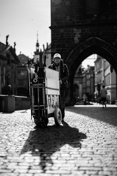 Person standing with bicycle on a cobblestone street beneath a historic stone archway.