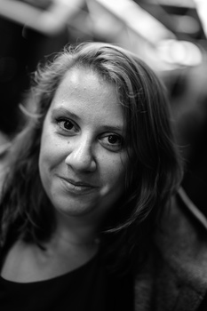 Black and white portrait of a woman with long dark hair, slight smile, looking directly at camera.