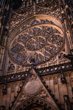 Ornate rose window of Gothic cathedral with intricate stone tracery and circular medallion below.