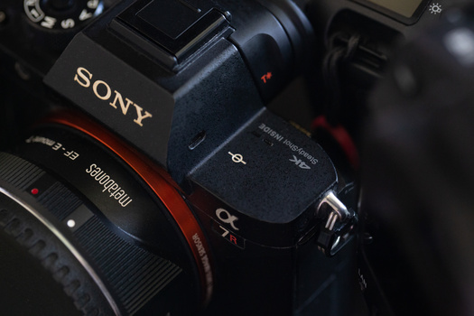 Sony camera body with attached lens and viewfinder against dark background.