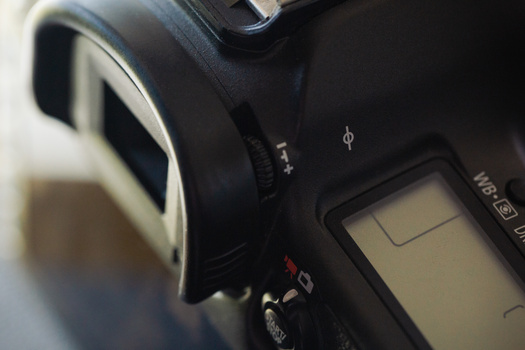 Close-up of a camera's back panel showing the LCD screen and control buttons in soft, angled lighting.