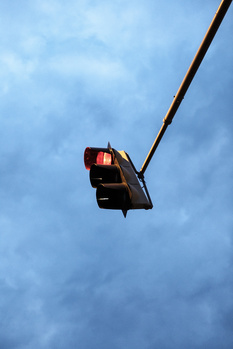 Traffic light mounted on wire against cloudy blue sky.