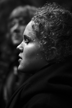Profile of a person with curly hair in monochrome against an unfocused background.