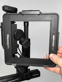 Matte box with filter tray mounted on camera rig, held by hand against white background.