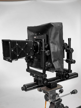 Large format camera mounted on tripod with bellows extended and lens board attached.