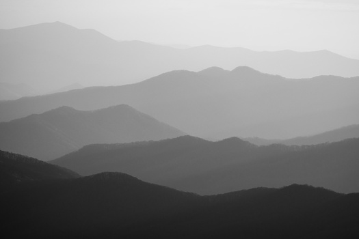 Layered mountain silhouettes fading into atmospheric haze, creating depth through tonal gradation.
