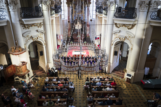 Elevated view of a grand baroque church interior during a formal ceremony with clergy and attendees.