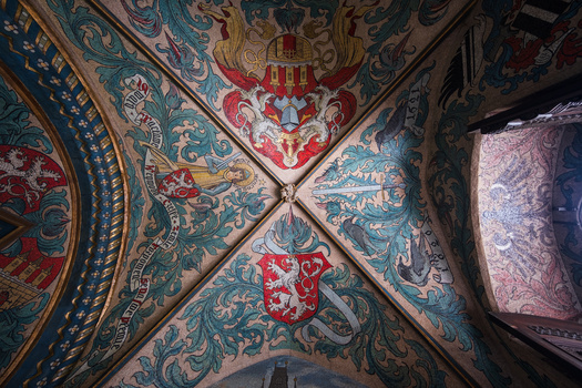 Ornate ceiling with symmetrical cross pattern and elaborate teal, red, and gold decorative paintings.