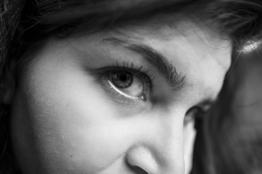 Close-up of a woman's eye and nose in black and white, showing defined eye makeup and contemplative gaze.