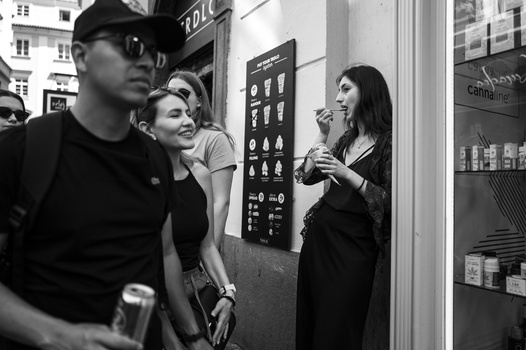 Three people examine a product display board in a retail storefront in black and white.