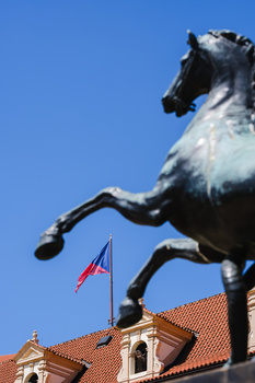 Black and white horse statue rearing up against a blue sky, with an American flag visible below.